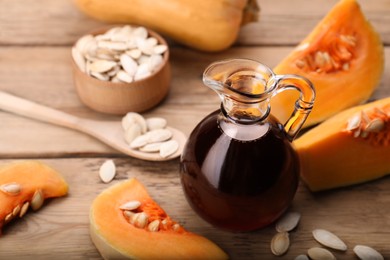 Photo of Fresh pumpkin seed oil in glass jug on wooden table