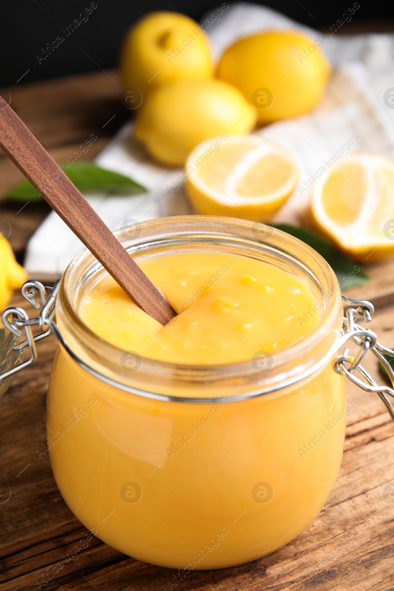 Photo of Delicious lemon curd in glass jar on wooden table