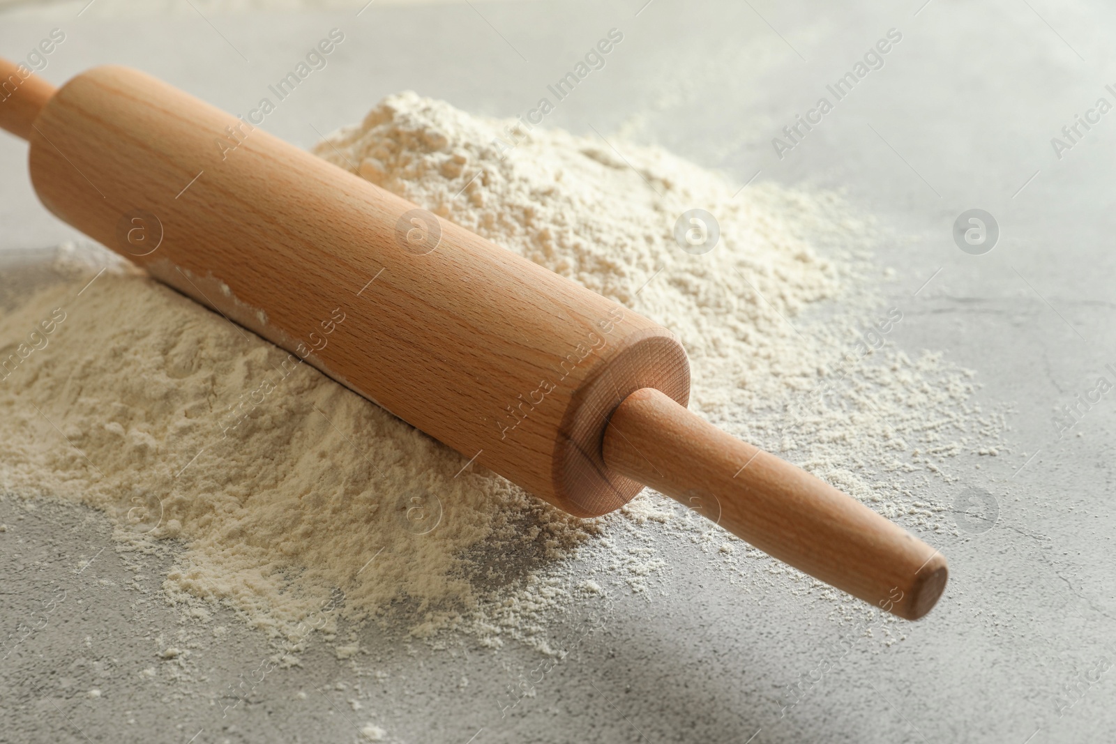 Photo of Flour and rolling pin on grey table, closeup
