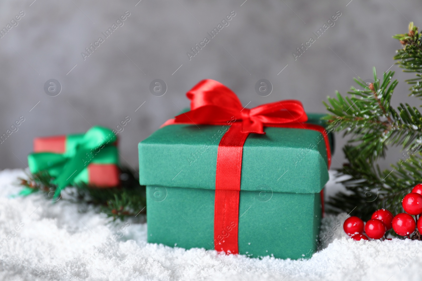 Photo of Christmas gift box on artificial snow against grey background, closeup