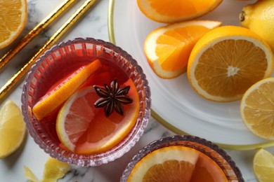 Photo of Aromatic punch drink and ingredients on white marble table, flat lay