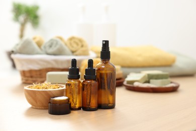 Photo of Bottles of essential oils, dry flowers and jar with cream on light wooden table, space for text. Spa therapy