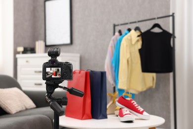Fashion blogger's workplace. Sneakers, shopping bags and clothes indoors, focus on camera
