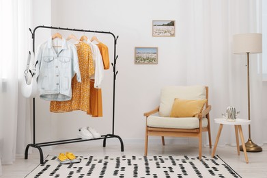 Photo of Stylish showroom interior with clothing rack and armchair