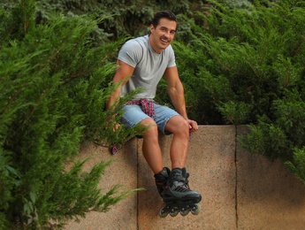 Handsome young man with roller skates outdoors