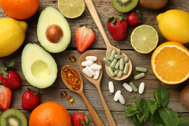 Photo of Different vitamin pills and fresh fruits on old wooden table, flat lay