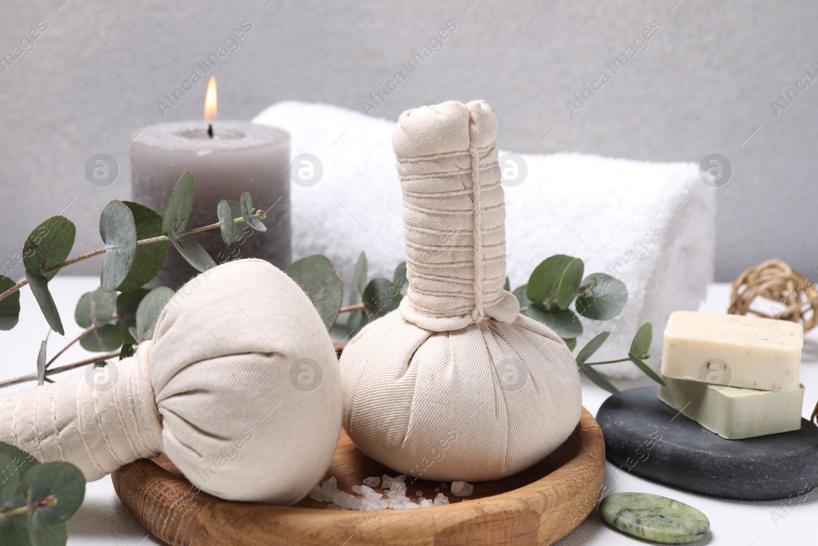 Photo of Spa composition with herbal massage bags and eucalyptus branches on white table