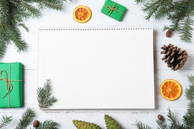 Photo of Flat lay composition with empty notebook and Christmas decorations on white wooden table, space for text. Writing letter to Santa Claus