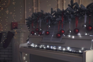 White piano with festive decor and note sheets indoors. Christmas music