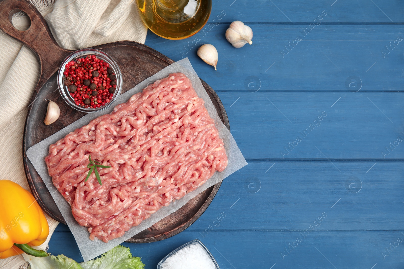 Photo of Raw chicken minced meat and ingredients on blue wooden table, flat lay. Space for text