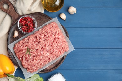 Photo of Raw chicken minced meat and ingredients on blue wooden table, flat lay. Space for text