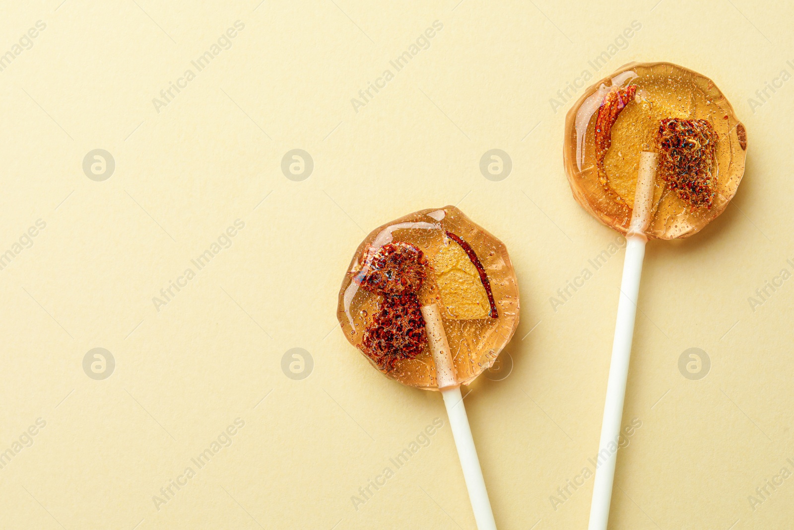 Photo of Sweet colorful lollipops with berries on beige background, flat lay. Space for text