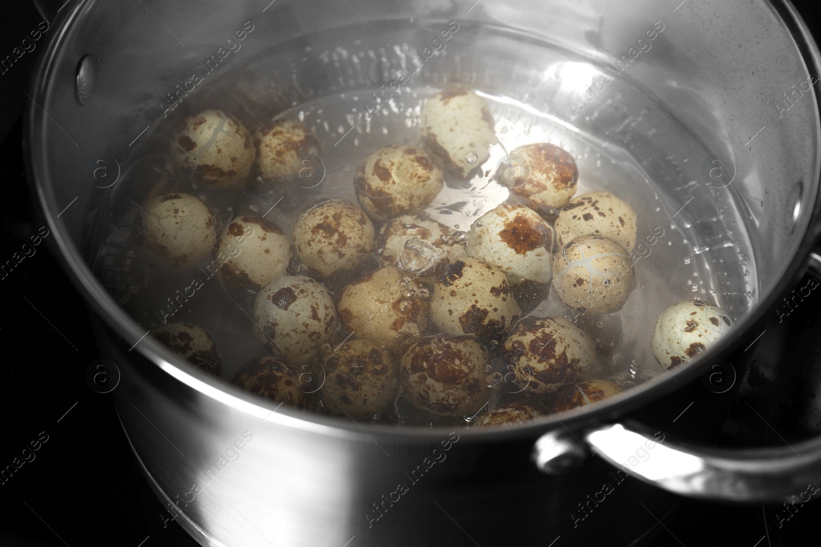 Photo of Cooking quail eggs in pot on electric stove, closeup