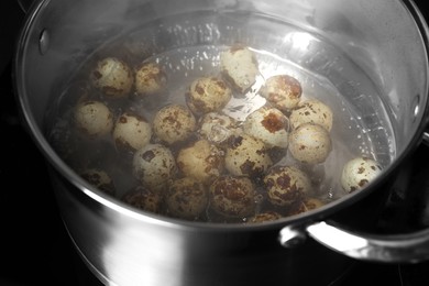 Cooking quail eggs in pot on electric stove, closeup
