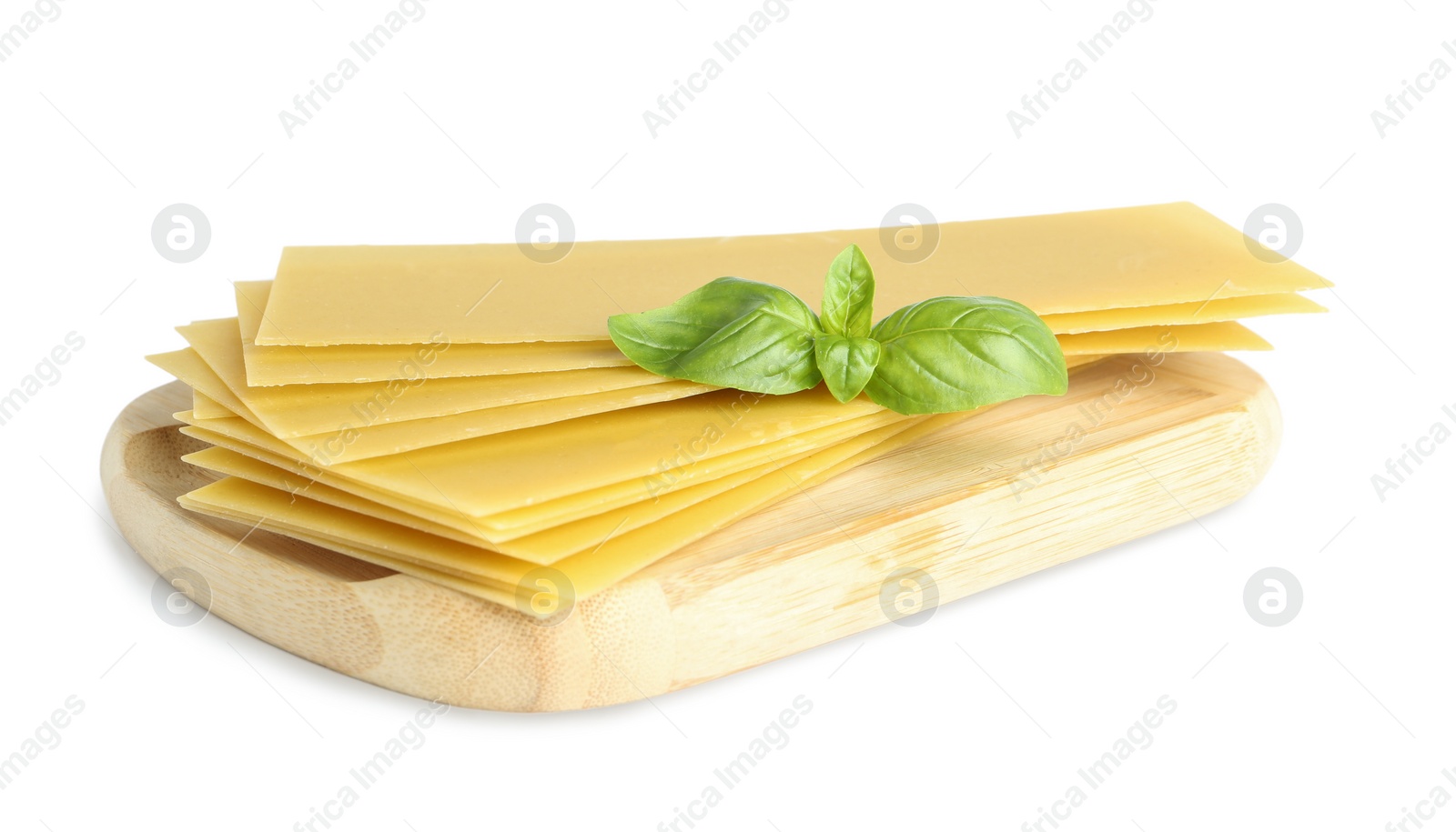 Photo of Wooden board with uncooked lasagna sheets and basil isolated on white