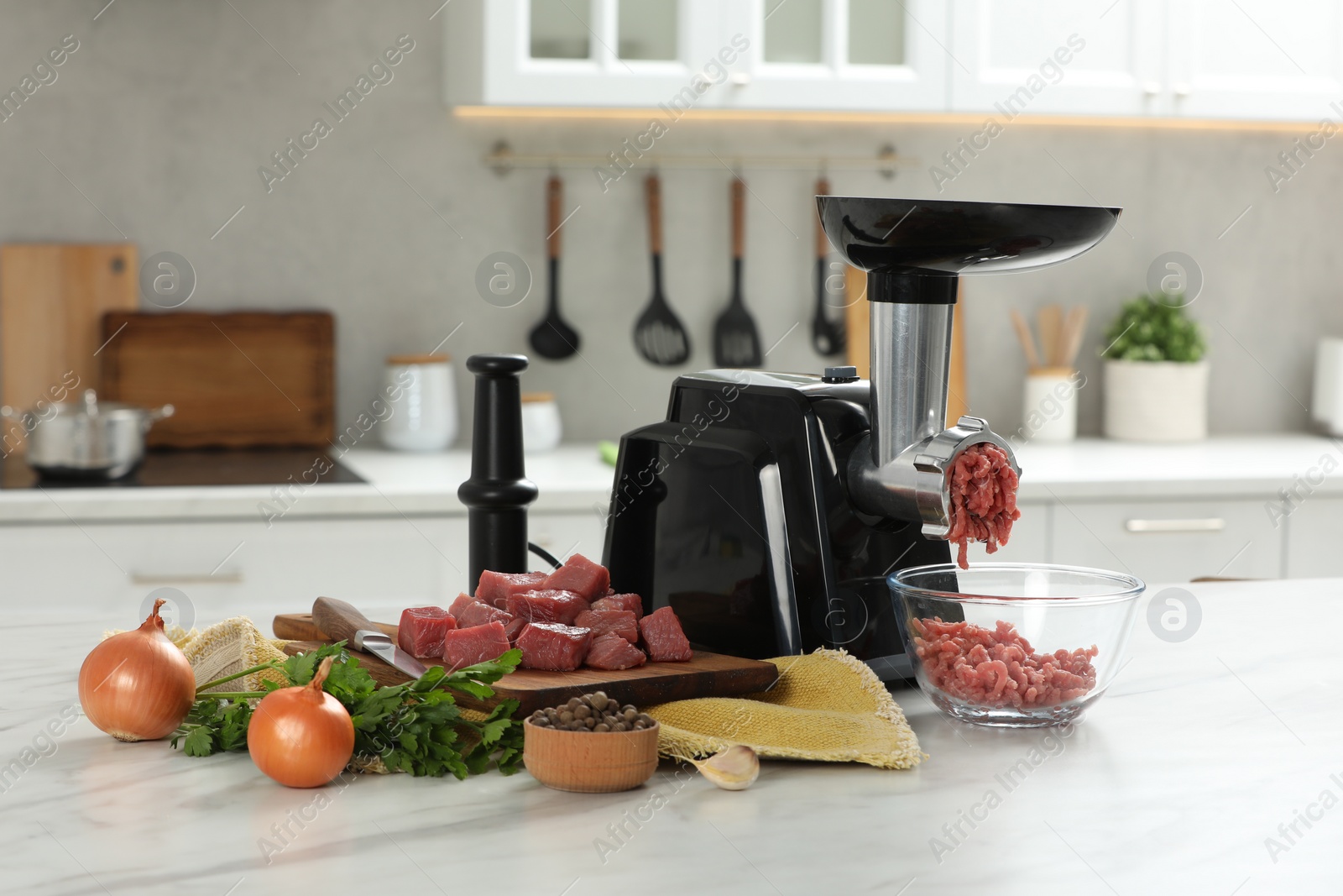Photo of Electric meat grinder with beef mince and products on white table in kitchen