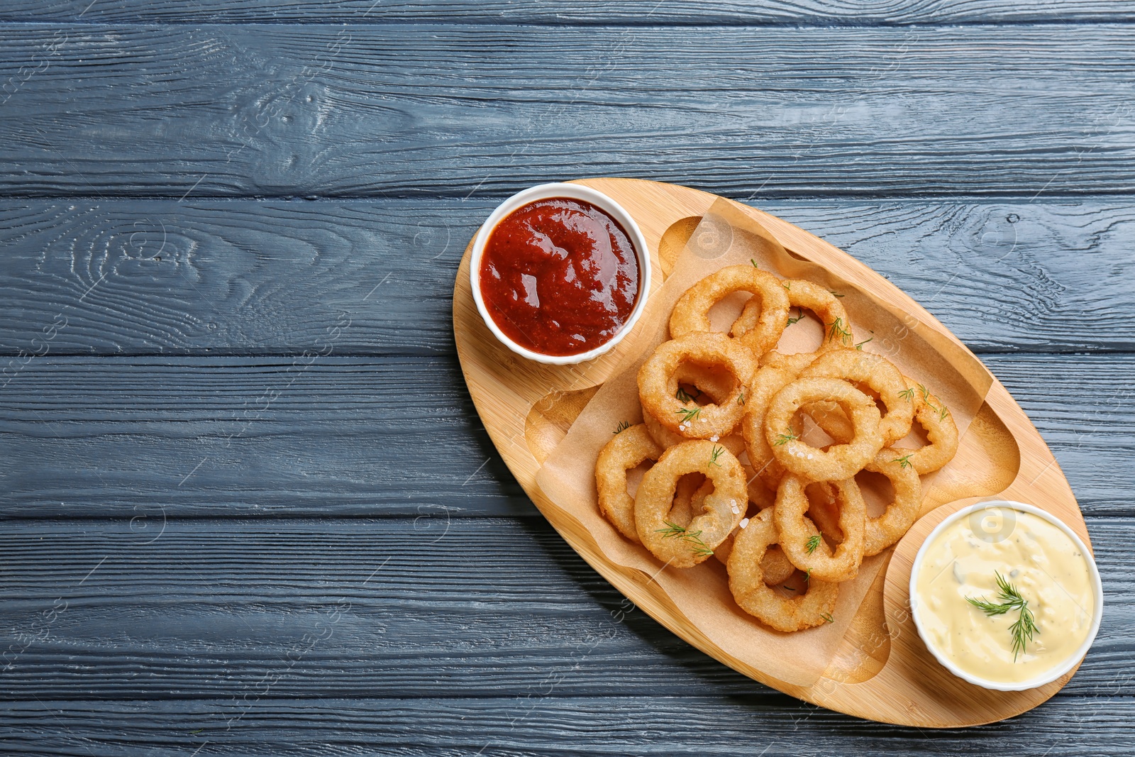 Photo of Fried onion rings served with sauces on plate, top view