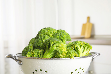 Photo of Raw green broccoli in colander indoors, closeup