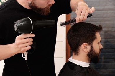 Photo of Professional hairdresser working with client in barbershop, closeup