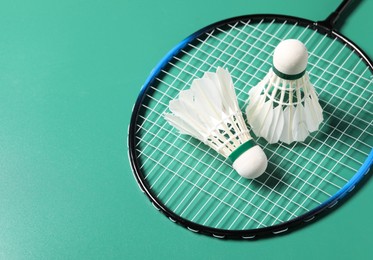 Photo of Feather badminton shuttlecocks and racket on green background. Space for text