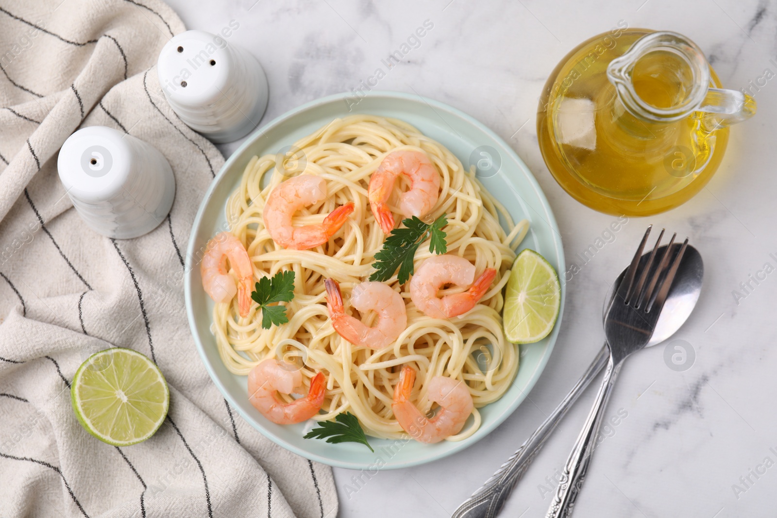 Photo of Tasty spaghetti with shrimps, lime and parsley served on white marble table, flat lay