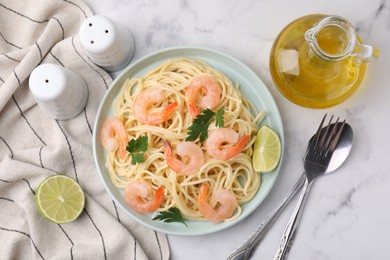 Photo of Tasty spaghetti with shrimps, lime and parsley served on white marble table, flat lay