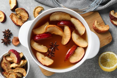 Delicious compote with dried apple slices and anise in pot on grey table, flat lay
