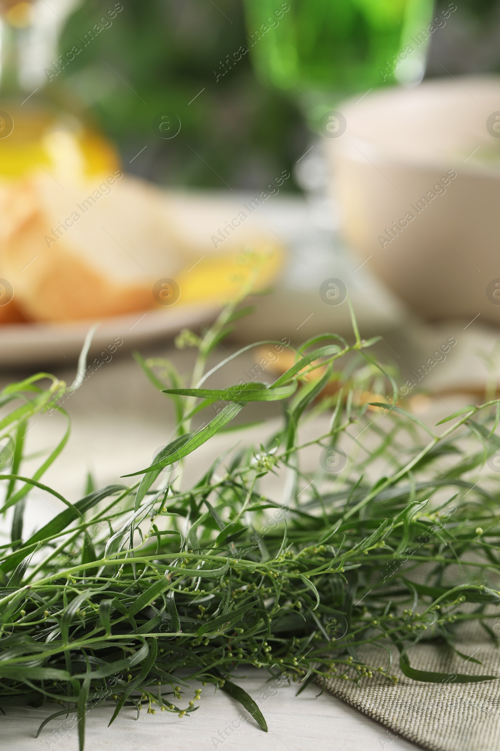 Photo of Fresh tarragon sprigs on white table. Space for text