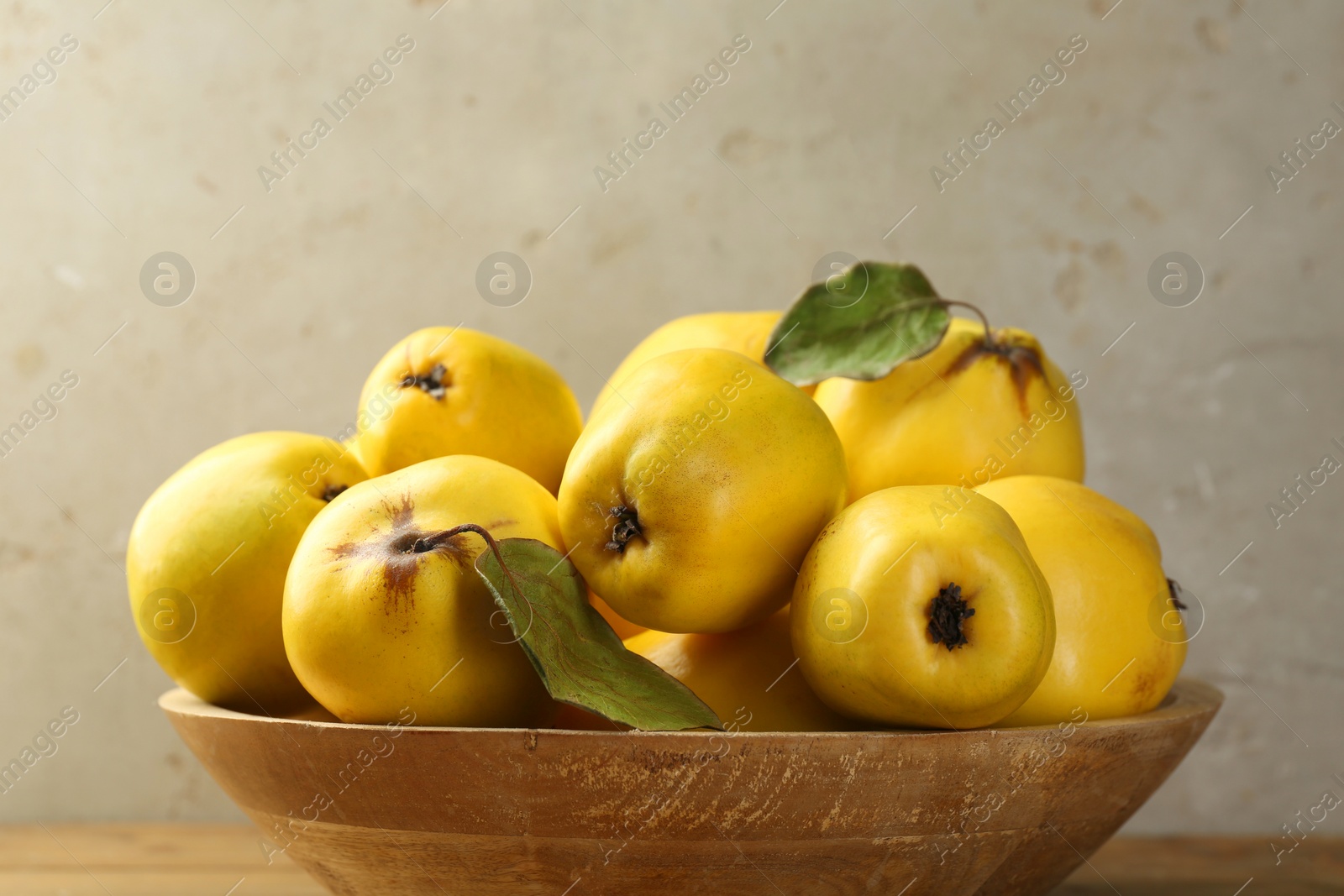 Photo of Tasty ripe quince fruits in bowl on table, closeup