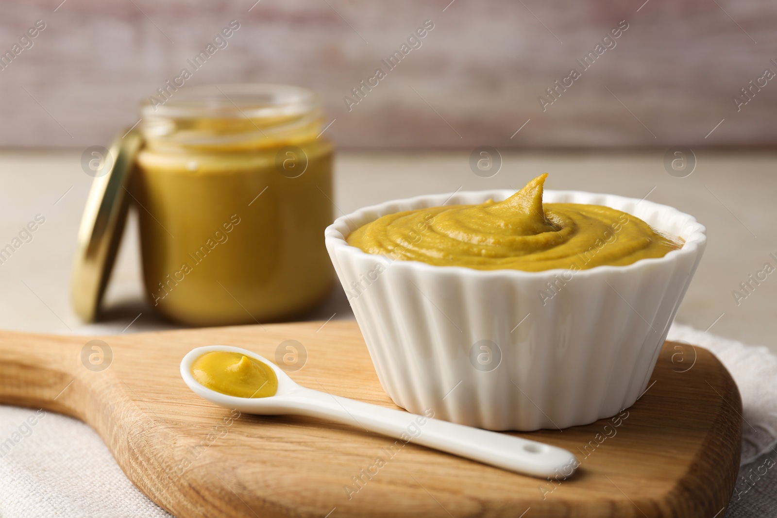 Photo of Bowl and spoon with tasty mustard sauce on light table