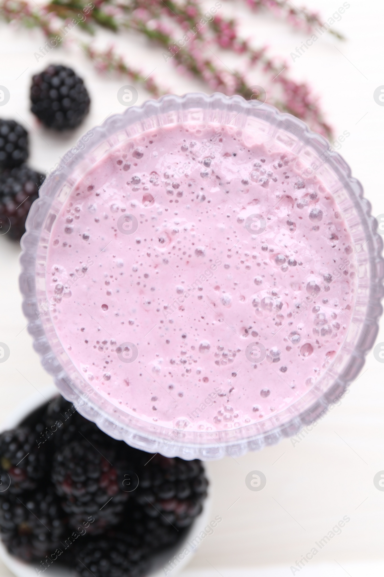 Photo of Delicious blackberry smoothie in glass on white wooden table, flat lay