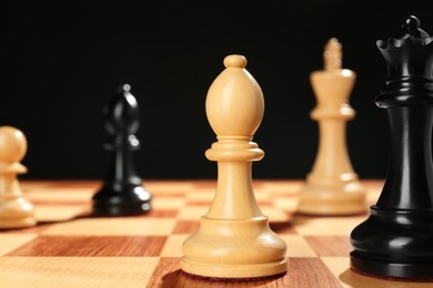Photo of Different game pieces on chessboard against dark background