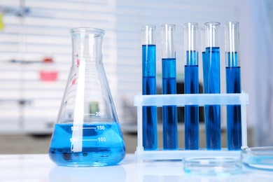 Photo of Laboratory analysis. Different glassware with blue liquid on white table indoors