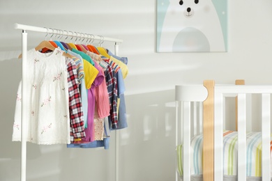 Photo of Different clothes hanging on rack in bedroom