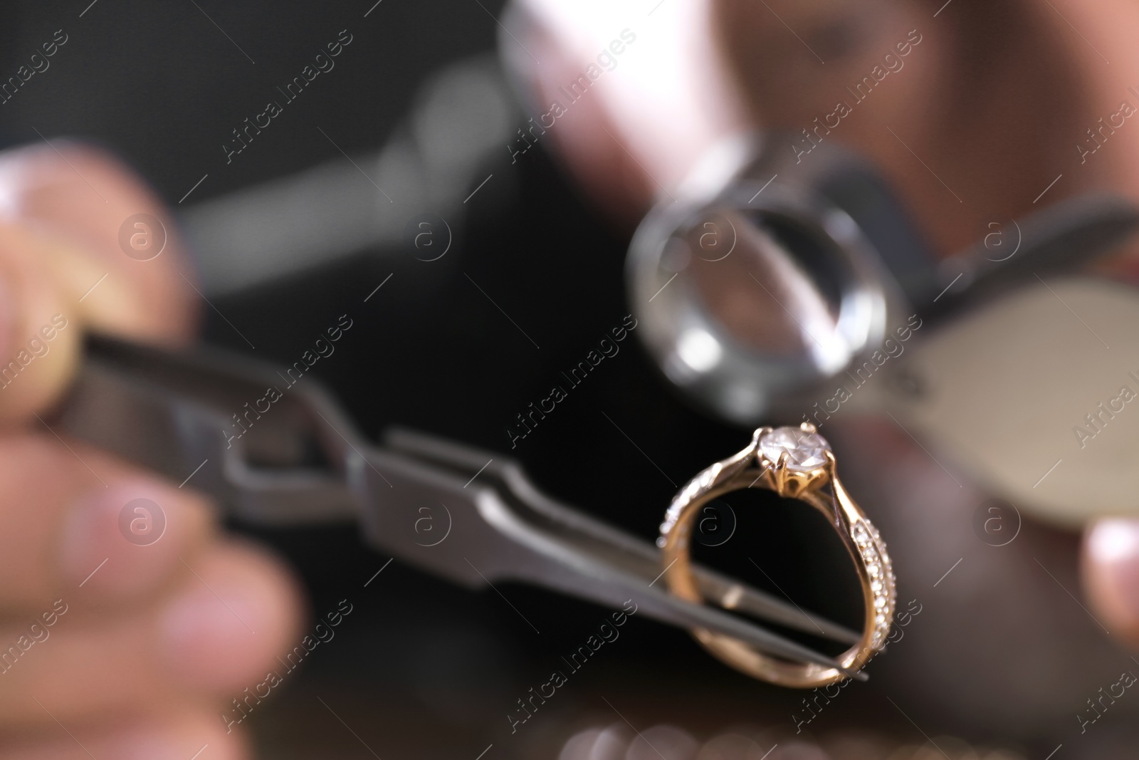 Photo of Male jeweler examining diamond ring in workshop, closeup view