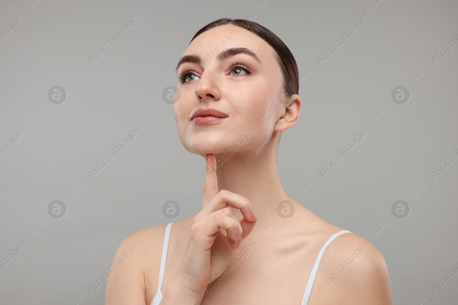 Photo of Beautiful woman touching her chin on grey background