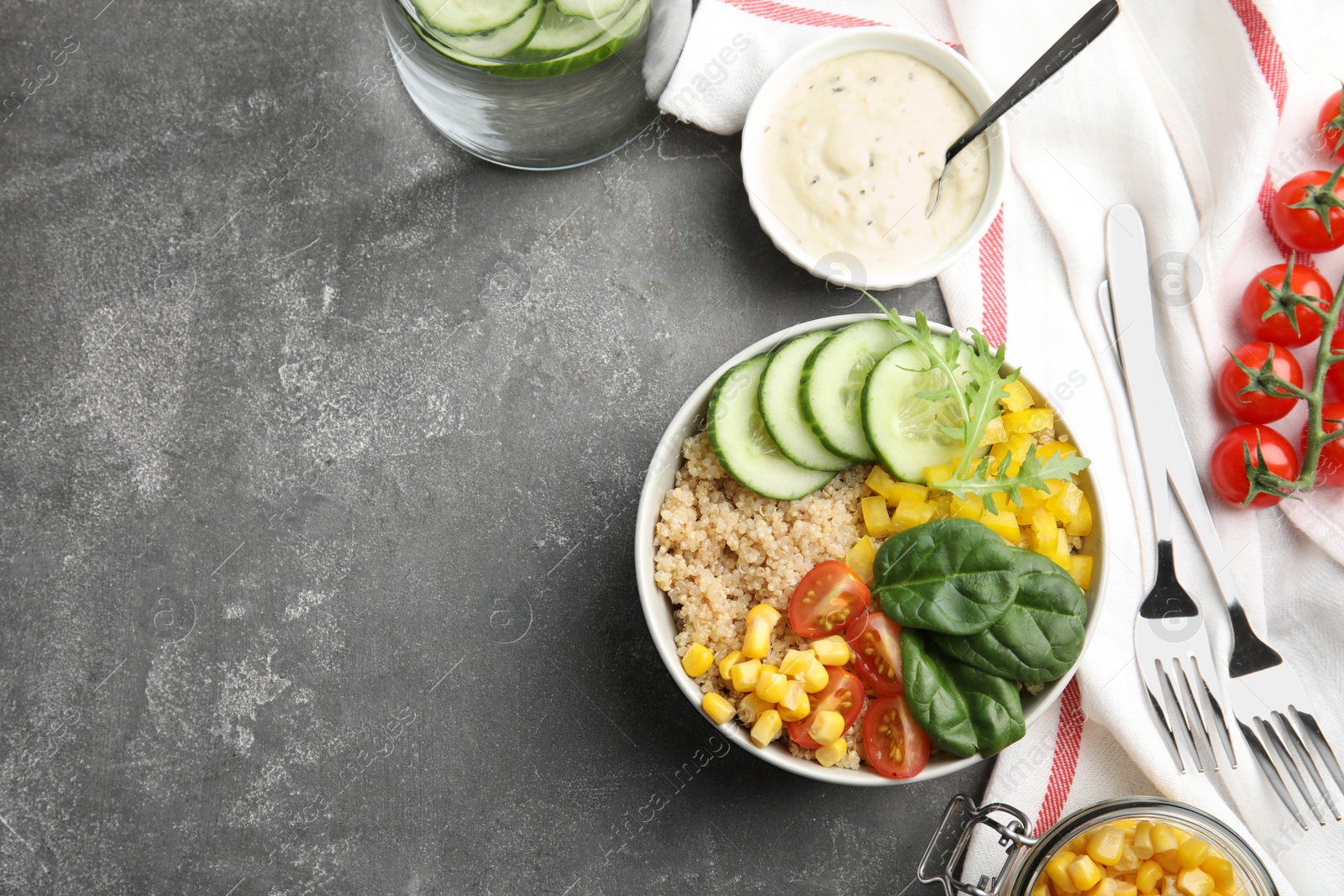 Photo of Healthy quinoa salad with vegetables in bowl served on grey table, top view. Space for text