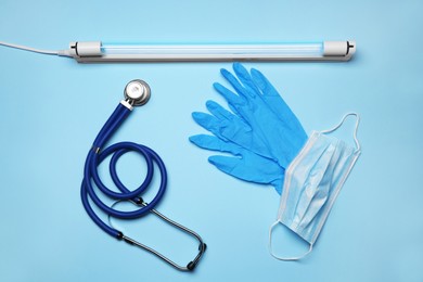 Photo of Flat lay composition with ultraviolet lamp on light blue background