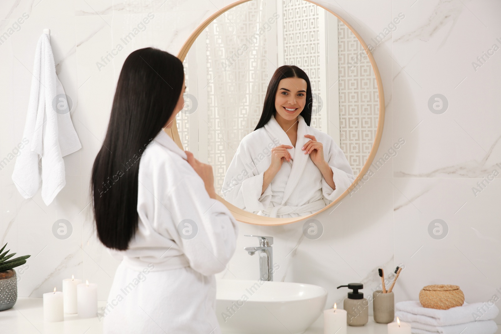 Photo of Beautiful young woman near mirror in bathroom