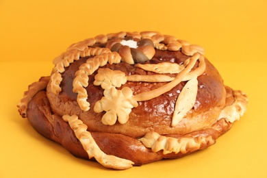 Photo of Fresh korovai on yellow background, closeup. Ukrainian bread and salt welcoming tradition