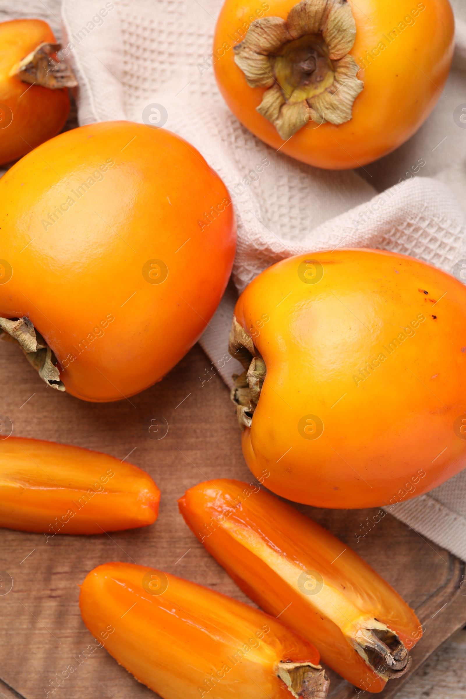 Photo of Whole and cut delicious ripe persimmons on wooden table, top view