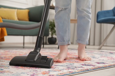 Woman cleaning carpet with vacuum cleaner at home, closeup. Space for text