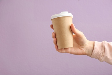 Woman holding takeaway paper coffee cup on color background. Space for design