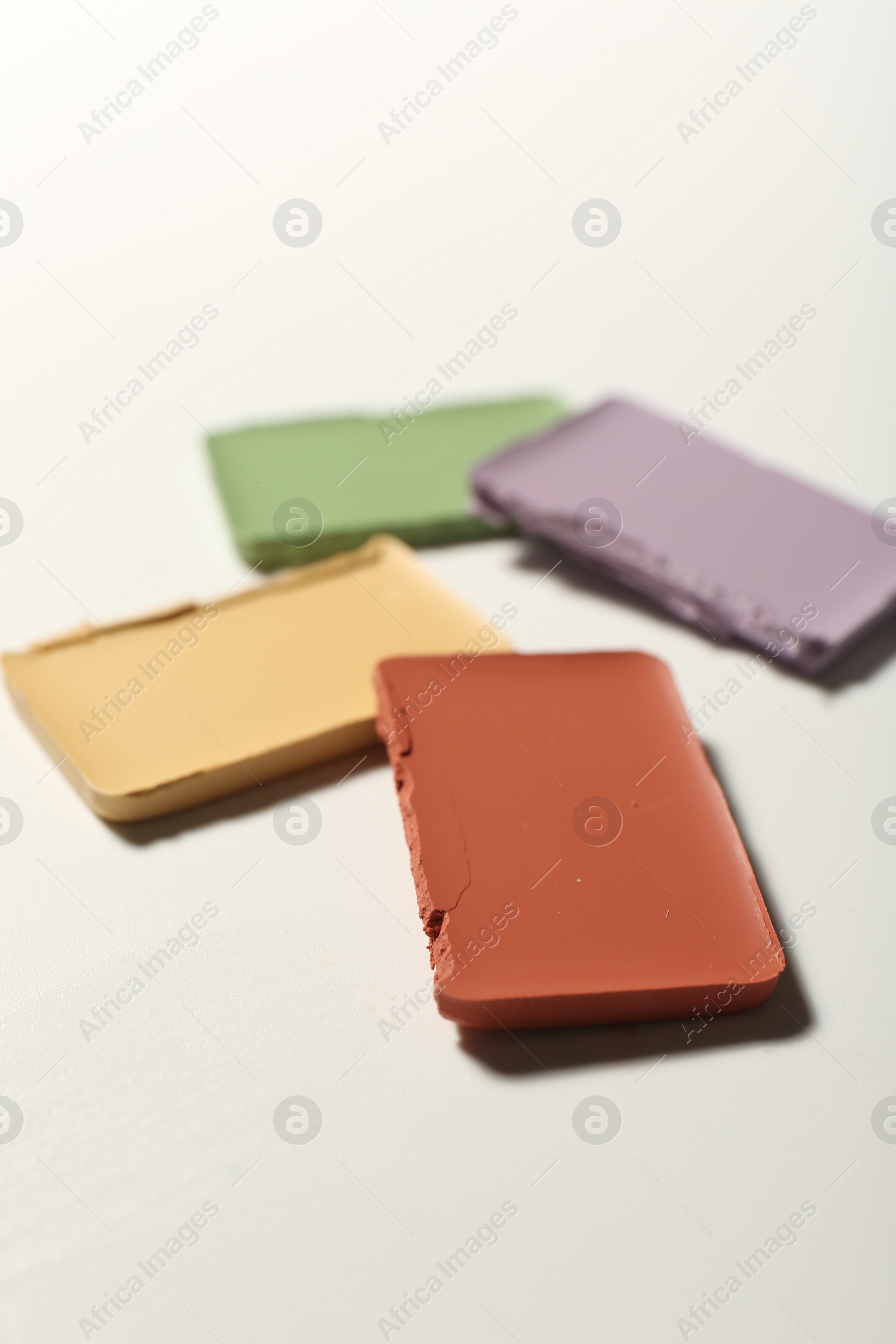 Photo of Different color correcting concealers on white background, closeup