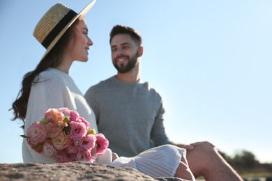 Photo of Happy young couple with flowers outdoors, focus on flowers. Honeymoon trip
