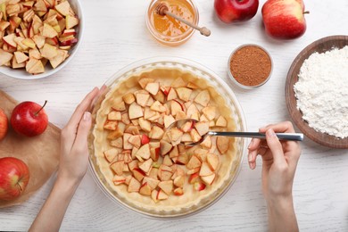 Photo of Woman cooking apple pie at white wooden table, top view