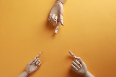 Photo of Wooden mannequin hands on orange background, flat lay