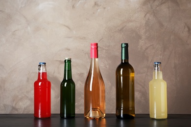 Photo of Bottles with different alcoholic drinks on table against color background