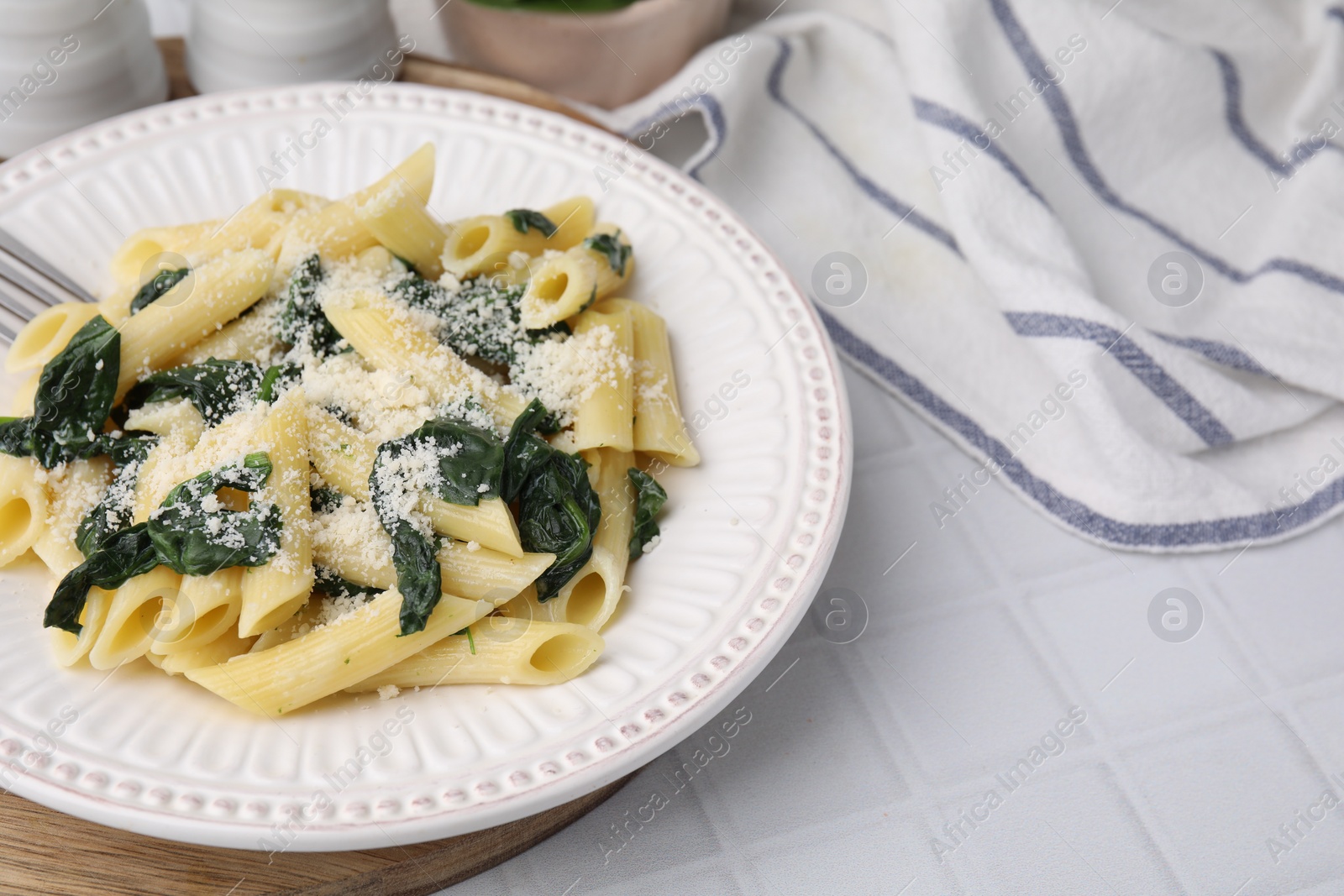 Photo of Tasty pasta with spinach and cheese on white tiled table, space for text