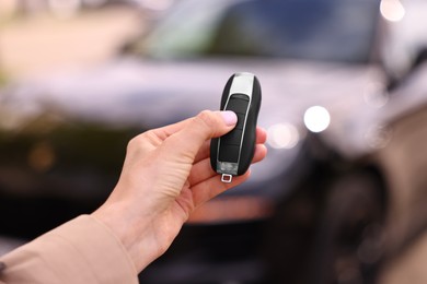 Photo of Woman holding car flip key near her vehicle outdoors, closeup